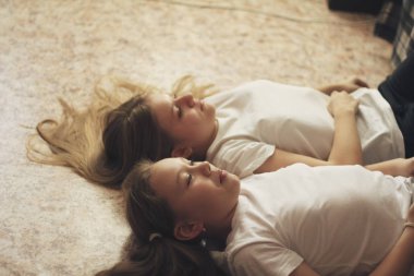 İki genç kız, yerde yatarken saçlarını yere yayıldı.
