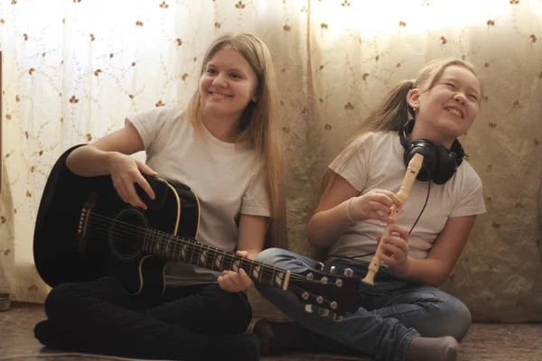 스마트폰 및 악기 집에서 바닥에 앉아 두 여자 청소년 — 스톡 사진