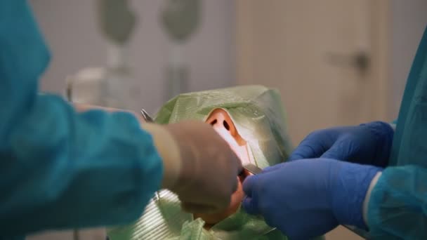 Лікар оглядає пацієнта з рефрактором в стоматологічному кабінеті — стокове відео