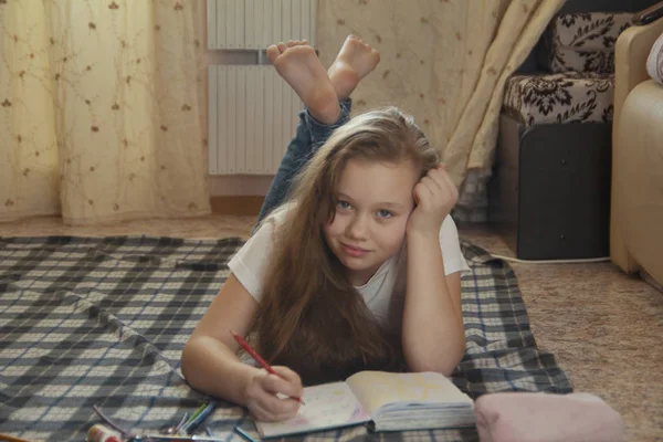 Jeune fille qui passe du temps à dessiner à la maison tout en étant couchée sur le sol — Photo