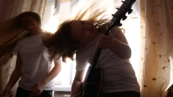 Duas adolescentes do sexo feminino têm unny e tocando música hard rock com instrumentos na frente da janela em casa — Vídeo de Stock