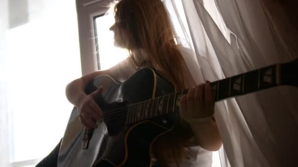 Молодая девушка-подросток играет на акустической гитаре дома, закрывается — стоковое видео