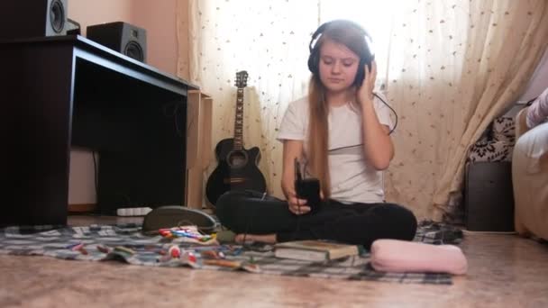 Gadis remaja mendengarkan musik di headphone di rumah — Stok Video