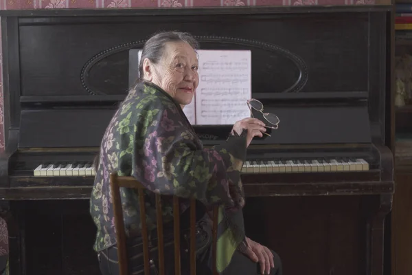 Vieja pianista sentada en el piano — Foto de Stock