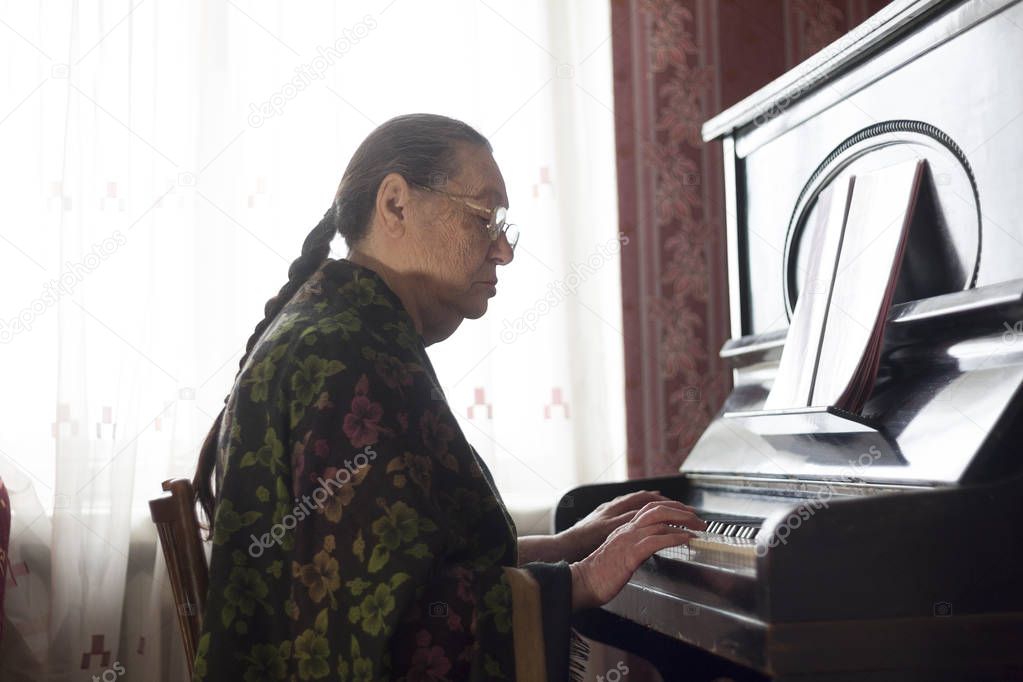 The old lady playing classical music on the rarity piano at home