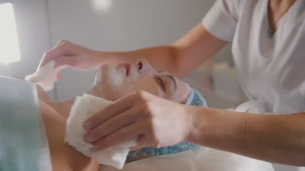 Mujer recibiendo un procedimiento cosmético - mascarilla masaje facial en el salón de spa cuidado de la piel — Vídeo de stock