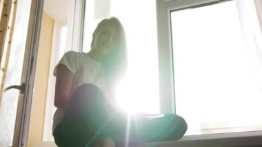 Pencere kenarında oturup kitap aracılığıyla saygısız genç ve güzel sarışın kız