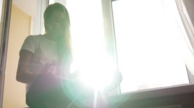 Genç ve güzel sarışın kız yiyor pasta ve pencere kenarında oturup kitap aracılığıyla flipping