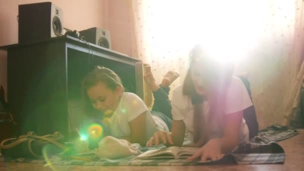 Duas meninas adolescentes lendo um livro e desenho enquanto estavam deitadas no chão em casa — Vídeo de Stock