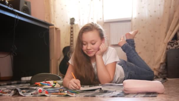 Jeune fille qui passe du temps à dessiner à la maison tout en étant couchée sur le sol — Video