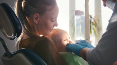 Mutlu anne resepsiyonda diş hekimi, diş bir sandalyede kızla
