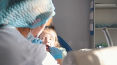 Küçük şirin kız dişçi ofisinde tedavi edilebilir, dirençli ve ağzını elleri ile kapanış istemiyor