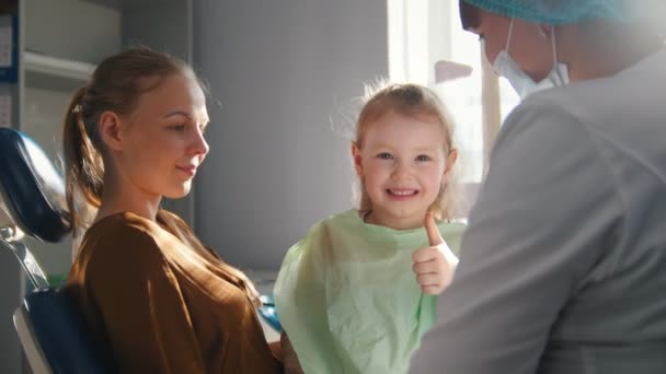 Маленький ребенок с мамой в стоматологии - показывает большой палец вверх — стоковое видео