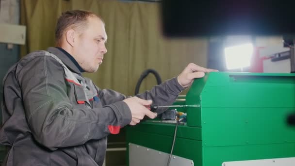 Arbetsprocesser reparerar en maskinen i fabriken med en skruvmejsel — Stockvideo