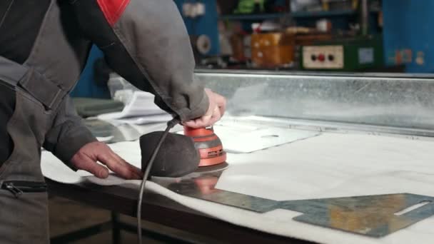 Primer plano de una lijadora manual controlada por un trabajador en la fábrica y lijado de una pieza metálica — Vídeos de Stock