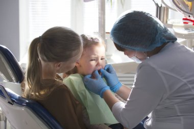 Kız, annesi ve diş hekimi diş office, incelenmesi ve danışmanlık stomatologist, kızı oynamaya ve şikayet