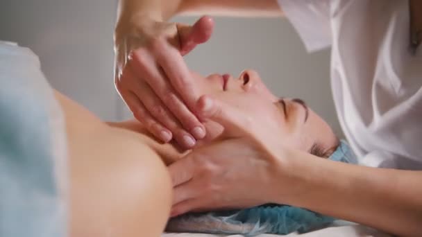Cosmetólogo hace un masaje especial en el cuello a su cliente para el levantamiento de la piel — Vídeos de Stock
