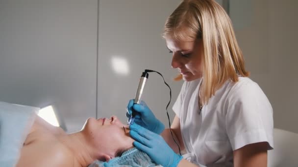 Cosmetologist fazendo uma massagem para levantar a pele do cliente com dispositivo especial — Vídeo de Stock