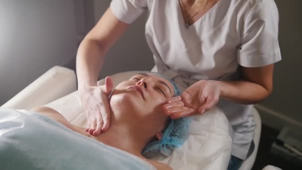 Cosmetologue appliquer de l'huile sur le cou et les épaules des clients après la procédure cosmétique — Video