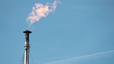 Fabrika boru ile gökyüzüne karşı yanan bir alev