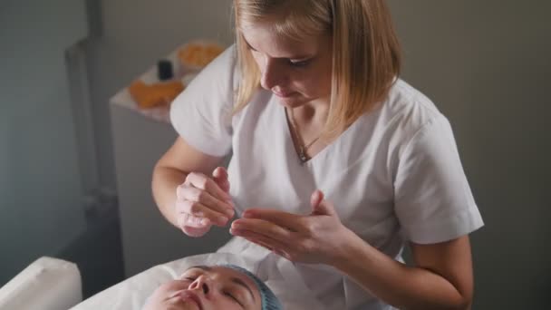 Cosmetologo pulizia clienti faccia con lozione speciale dopo la procedura cosmetica — Video Stock