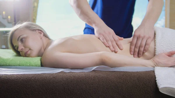 Mans van de handen op de rug van het meisje in de massage salon — Stockfoto