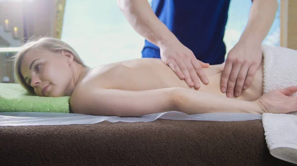 Mans hands on the back of the girl in massage parlor — Stock Photo, Image