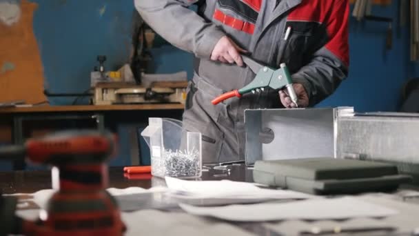 ペンチで金属部分を手で組み立てる労働者がフォア グラウンドで金属と金属の詳細を研削用ツールします。 — ストック動画