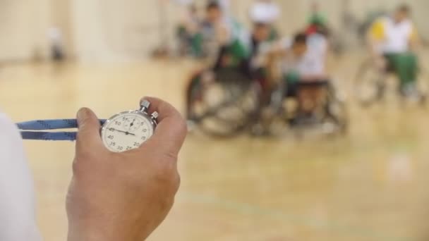 Stopwatch in de hand van coach tijdens opleiding voor rolstoelbasketbal, slow-motion — Stockvideo