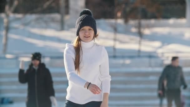 Adolescente menina habilmente patinando no ringue de gelo público ao ar livre, câmera lenta — Vídeo de Stock