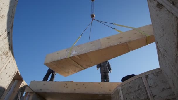 Pohled z domu - práce stavební jeřáb výtahy slámy dřevěný blok pro kruh ekologie dům — Stock video