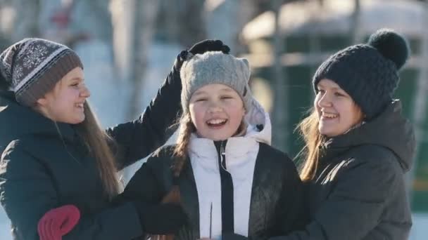 Porträt von drei Teenager-Mädchen, die im Winter draußen posieren, sich umarmen und lächeln — Stockvideo