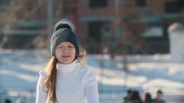 Chica adolescente hábilmente patinaje en pista de hielo pública al aire libre, cámara lenta — Vídeos de Stock