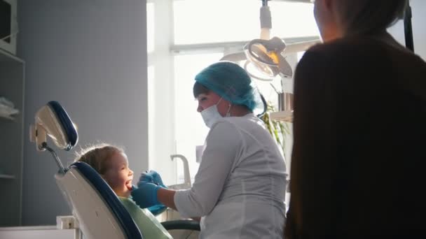 Bambina con la mamma sulla sedia del dentista - bambino sta giocando — Video Stock