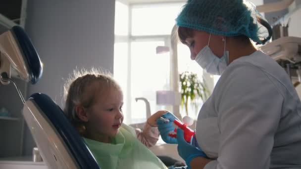 Little cute girl in the dentists office does not want to be treated, resisting and closing her mouth with her hands — Stock Video