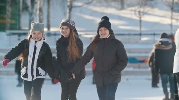 Дві дівчини-підлітки катаються на ковзанах і тримаються один за одного — стокове відео