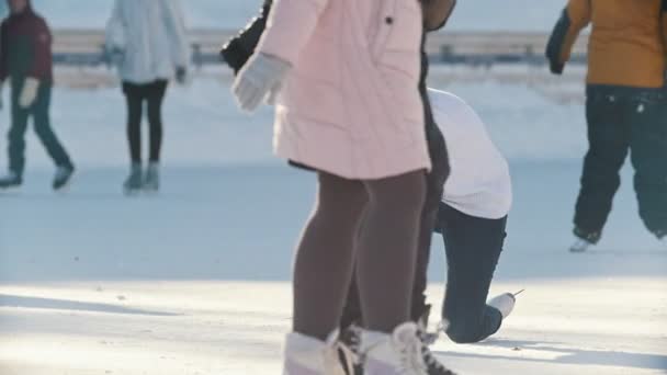 Patinaje chica rusa patinaje, caída y de pie en una pista de hielo pública — Vídeo de stock