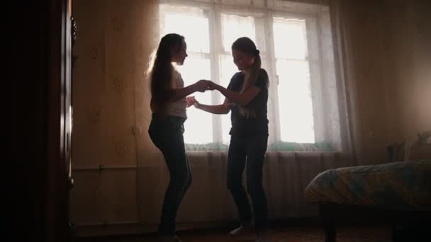 Chicas jóvenes riendo y girando en la habitación de casa delante de la ventana soleada — Vídeos de Stock