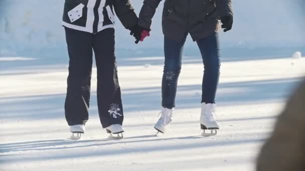 Две девушки-подростки учатся кататься на коньках и веселиться - ноги закрываются — стоковое видео