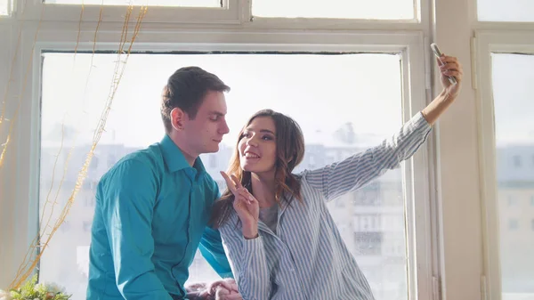 Νέοι και ελκυστική άνδρας και η γυναίκα που κάνει μια selfie που κάθεται στο παράθυρο — Φωτογραφία Αρχείου