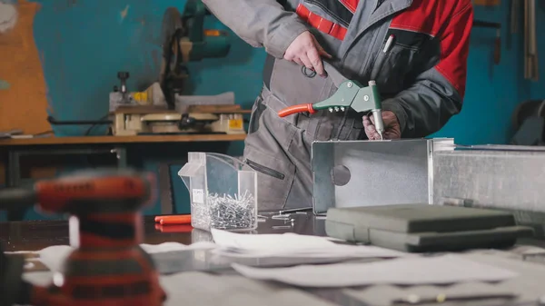 Arbeiter montieren das Metallteil von Hand mit einer Zange, Werkzeug zum Schleifen von Metall und Metalldetails im Vordergrund — Stockfoto