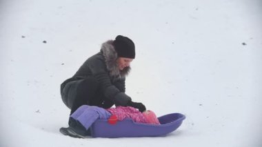 Anne küçük kızı ile konuşurken bir kızak kış Park içinde yatan