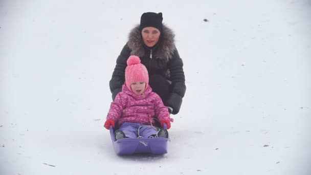 Máma postupných její malá dcera na saních v destinaci winter park — Stock video