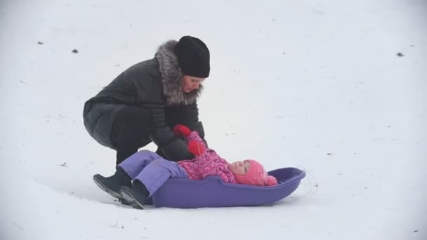 妈妈把他不听话的女儿放在雪橇上过冬的街道上 — 图库视频影像