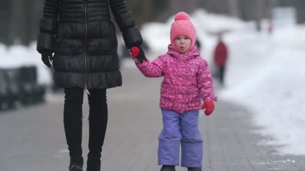 Милая маленькая девочка идет со своей матерью на зимней улице, дочь убегает и собирается самостоятельно — стоковое видео