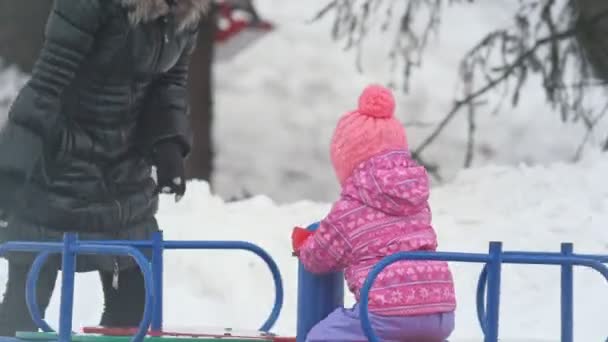 Moeder haar dochtertje op de carrousel cirkelen in de winter — Stockvideo