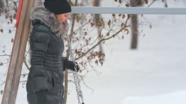 Sevimli küçük kızını kışın üzerinde parkta salıncakta sallanan anne