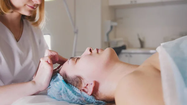 Donna medico esegue procedura cosmetica - maschera massaggio facciale al salone termale cura della pelle — Foto Stock