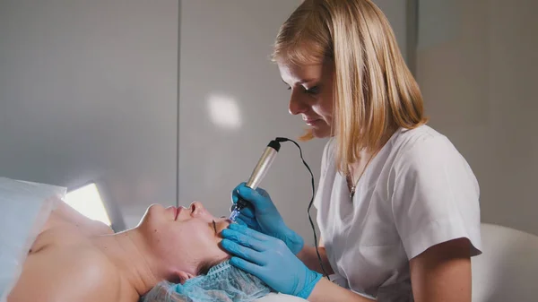 Косметолог робить спеціальний масаж для свого клієнта для підтяжки обличчя — стокове фото