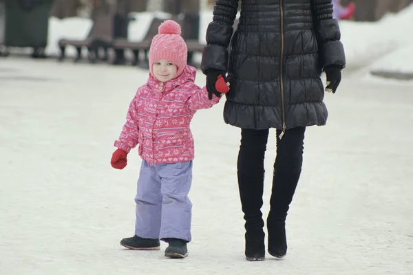 Schattig meisje wandelen in de sneeuw en vallen in de snowbank voor een wandeling met haar moeder — Stockfoto